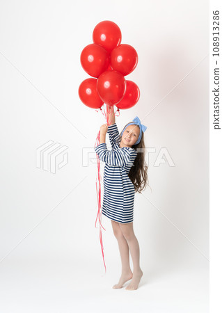 Girl holding large bunch red balloons in hands, smiling and looking at camera on white background Girl holding large bunch red balloons in hands, smiling and looking at camera on white background 108913286