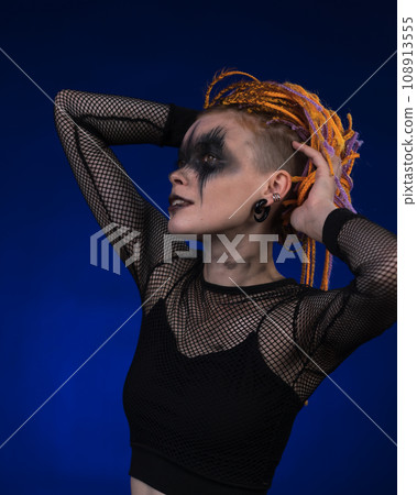 Female with orange color braids hairdo and horror black stage makeup painted on face 108913555