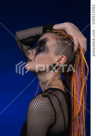 Cinematic portrait of informal woman with colored braids hairdo and horror black stage make-up 108913562