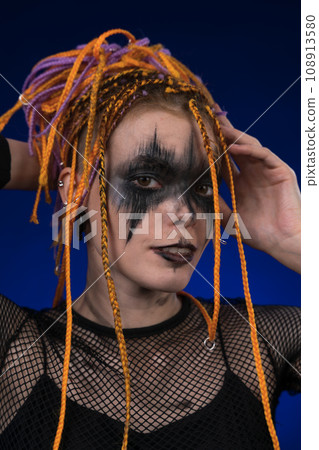 Informal young woman with colored dreadlocks hairstyle, horror black stage make up painted on face Informal young woman with colored dreadlocks hairstyle, horror black stage make up painted on face 108913580