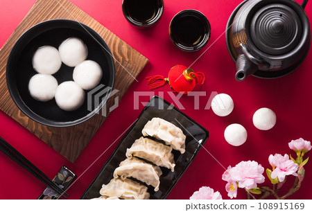 Tang Yuan(sweet dumplings balls), a traditional cuisine for Mid-autumn, Dongzhi (winter solstice ) and Chinese new year with plum flower and tea on red background. Tang Yuan(sweet dumplings balls), a traditional cuisine for Mid-autumn, Dongzhi (winter solstice ) and Chinese new year with plum flower and tea on red background. 108915169