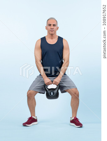 Full body length shot athletic senior man doing squat with weight. Clout 108917652