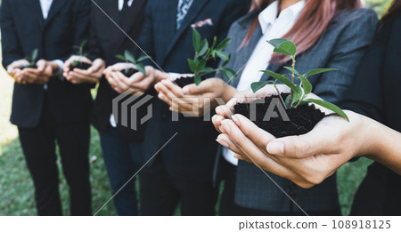 Business people holding plant or sprout together in unity as CSR commitment.Gyre 108918125