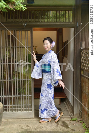 一位穿著浴衣的年輕女子在一座古老民宅的入口處 108918722