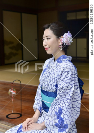 A young woman wearing a yukata on the porch of an old folk house 108919936