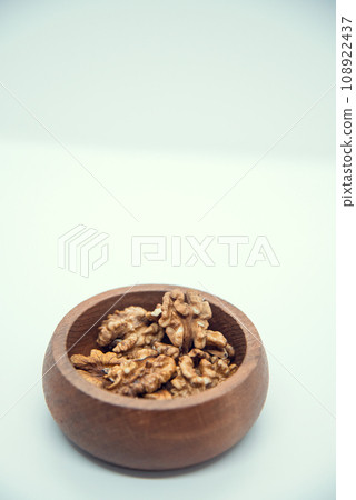Walnut kernel halves, in a wooden bowl on white background. Close-up Walnut kernel halves, in a wooden bowl on white background. Close-up 108922437