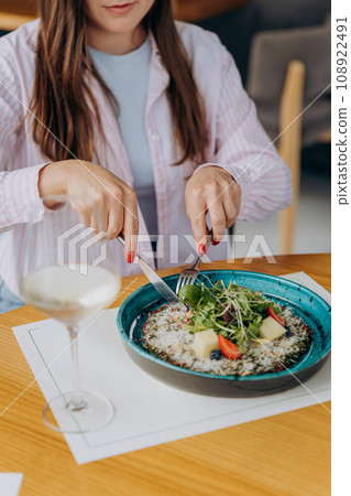 Young attractive woman enjoys tasty meal on cafe or restaurant background 108922491