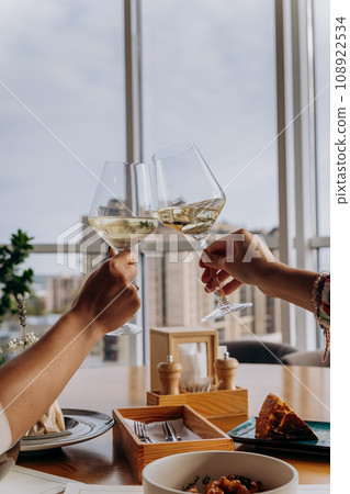 Close up of hands toasting wine glasses at dinner in restaurant. Drinks and celebration concept 108922534