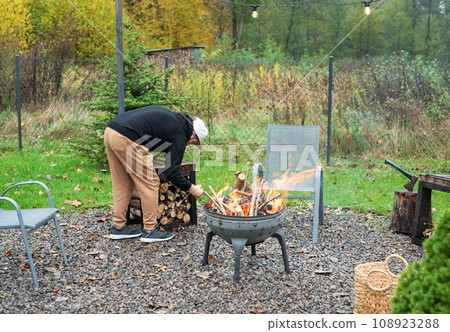 A man lights a barbecue in nature A man lights a barbecue in nature 108923288
