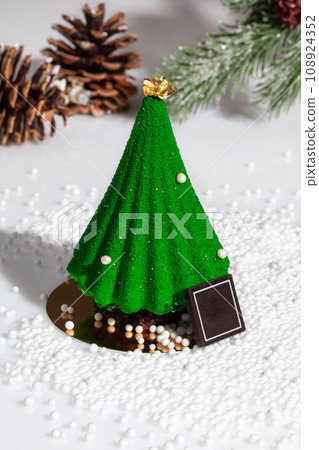 Green Christmas tree shaped cake with fir branch and cones 108924352