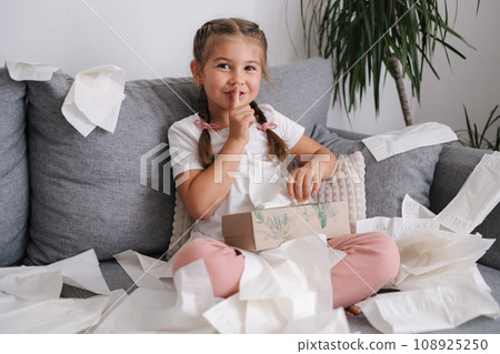 Five year old girl scattered napkins around the sofa. Cunning daughter made a mess at home Five year old girl scattered napkins around the sofa. Cunning daughter made a mess at home 108925250