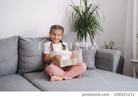 Adorable little girl take packing of napkins and have fun. Kid make a mess at home Adorable little girl take packing of napkins and have fun. Kid make a mess at home 108925251