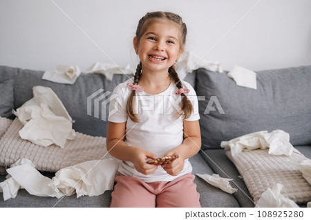 Little girl eats chocolate alone at home. Mess and chaos at home.  108925280