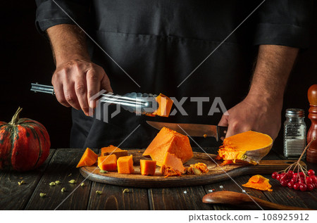 Cooking a national delicious pumpkin dish with the hands of a professional chef in a restaurant kitchen. Work environment on the kitchen table with spices and viburnum. Cooking a national delicious pumpkin dish with the hands of a professional chef in a restaurant kitchen. Work environment on the kitchen table with spices and viburnum. 108925912