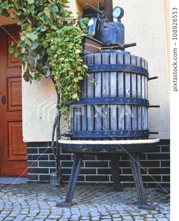 An old historic wine press. The press serves as a decoration and holds creeping plants An old historic wine press. The press serves as a decoration and holds creeping plants 108926553
