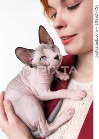 Hipster young redhead woman hugging cat. Selective focus on domestic kitten, shallow depth of field 108927755