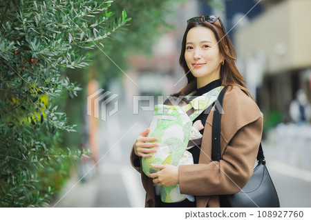 A mother goes out with her baby in a baby carrier 108927760