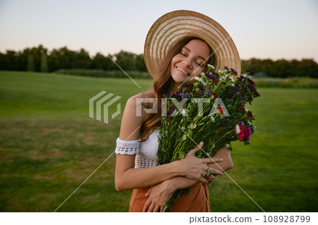 Beautiful hipster woman holding bunch of wildflower Beautiful hipster woman holding bunch of wildflower 108928799