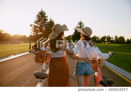 View from back on two female friends exploring nature on bikes outdoors 108928857