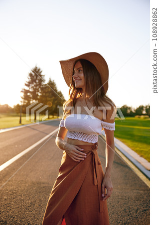 Portrait of charming hipster woman in straw hat over road Portrait of charming hipster woman in straw hat over road 108928862