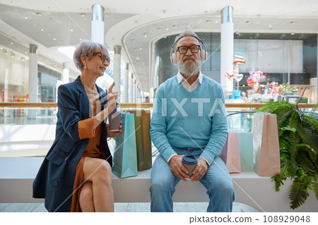 Elderly couple in shopping mall, husband avoiding communication with his wife 108929048