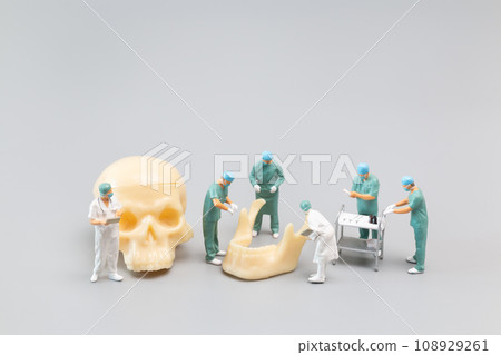 Miniature people Doctor with a giant human skull on a grey background 108929261