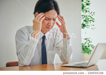 一名身穿 Y 恤的男性辦公室職員把手放在額頭上 108930106