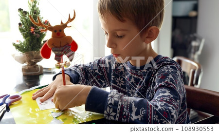 Portrait of concentrated boy in pajamas writing letter to Santa with his wishes on Christmas 108930553