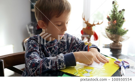 Closeup portrait of little boy in pajamas writing letter to Santa on Christmas morning 108930554