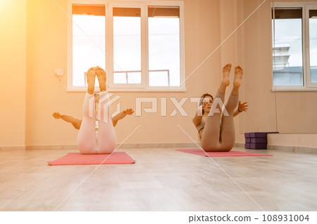 Two beautiful women do yoga, sports in the gym. The concept of grace and beauty of the body. Two beautiful women do yoga, sports in the gym. The concept of grace and beauty of the body. 108931004