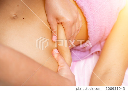 Top view of hands massaging female abdomen.Therapist applying pressure on belly. Woman receiving massage at spa salon 108931043