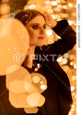 Christmas mood. Woman with long hair in sity decorated for Christmas. She is dressed in a black coat. 108931066
