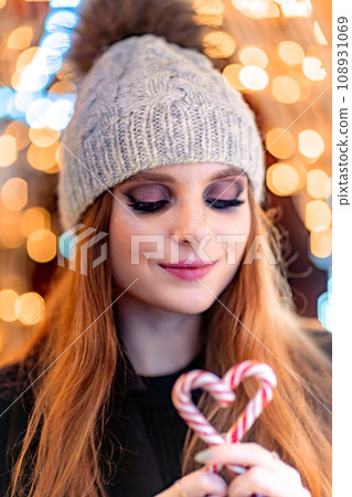 Christmas mood. Woman with long hair in sity decorated for Christmas. She is dressed in a black coat. Christmas mood. Woman with long hair in sity decorated for Christmas. She is dressed in a black coat. 108931069