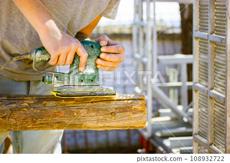 Hands of faceless craftsman using polishing machine on wooden logs. Working on wood with woodworking machine. Carpenter, engineer master working hard. Electric polisher, Orbital sander. Man is working 108932722