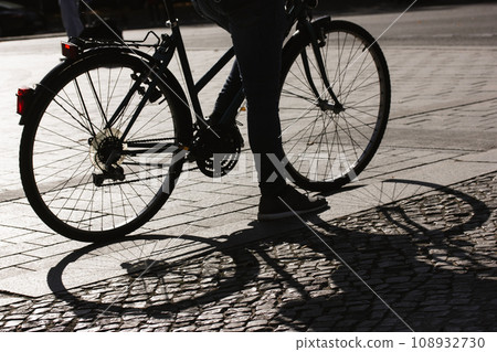 Contrast shadow of an old classic two-wheeler, wheels on a pavement. Cyclist traveling on eco-friendly transportation in urban environment. Modern lifestyle. City street photography. Bike trip. Contrast shadow of an old classic two-wheeler, wheels on a pavement. Cyclist traveling on eco-friendly transportation in urban environment. Modern lifestyle. City street photography. Bike trip. 108932730