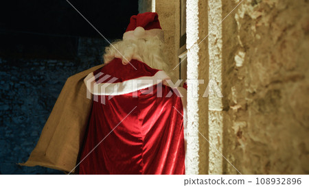 Santa Claus entering an old House for Christmas Santa Claus entering an old House for Christmas 108932896