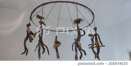 small straw dolls hanging on a chandelier 108934035