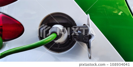Fueling electricity at an electric car at a charging station - close-up Fueling electricity at an electric car at a charging station - close-up 108934041