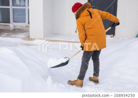 Man cleaning snow from sidewalk and using snow shovel. Winter season 108934250