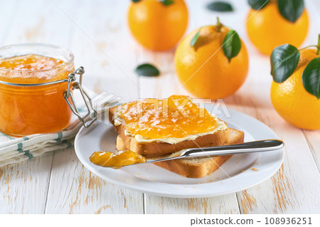 Toast with tasty orange jam on a white wooden table. 108936251