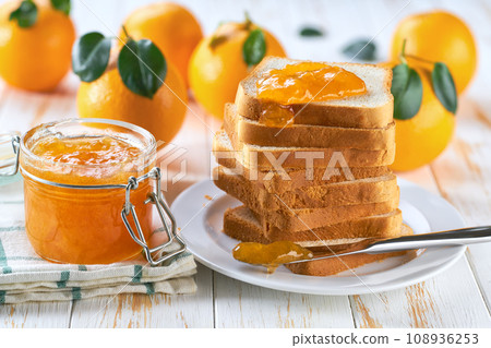 A stack of toasts with orange jam on a dish close-up. Plate with pieces of toasted bread and tasty orange jam. A stack of toasts with orange jam on a dish close-up. Plate with pieces of toasted bread and tasty orange jam. 108936253