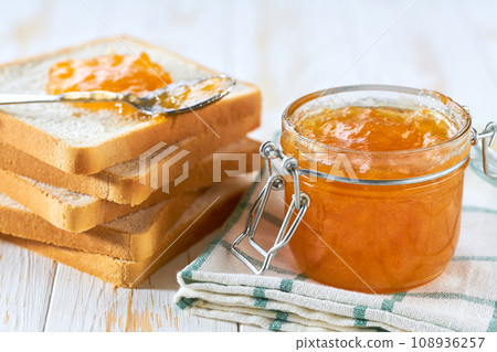Delicious orange jam on table close-up. Bread and orange homemade jam on wooden table. Delicious orange jam on table close-up. Bread and orange homemade jam on wooden table. 108936257