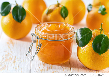 orange jam in jar and ripe oranges on a wooden table. Orange marmalade or orange jam in glass jar. orange jam in jar and ripe oranges on a wooden table. Orange marmalade or orange jam in glass jar. 108936259