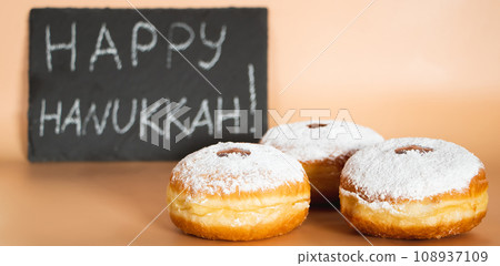 Happy Hanukkah. Traditional Jewish dessert Sufganiyot. Celebrating Judaism holiday. Donuts with jam and sugar powder. Happy Hanukkah. Traditional Jewish dessert Sufganiyot. Celebrating Judaism holiday. Donuts with jam and sugar powder. 108937109