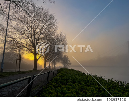 Sunrise over the river in the early morning with fog on the banks 108937128
