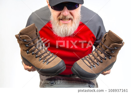 Tourist advertises and shows trekking boots. Clothing for tourism and travel Tourist advertises and shows trekking boots. Clothing for tourism and travel 108937161