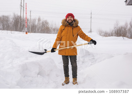 Man cleaning snow from sidewalk and using snow shovel. Winter season Man cleaning snow from sidewalk and using snow shovel. Winter season 108937387