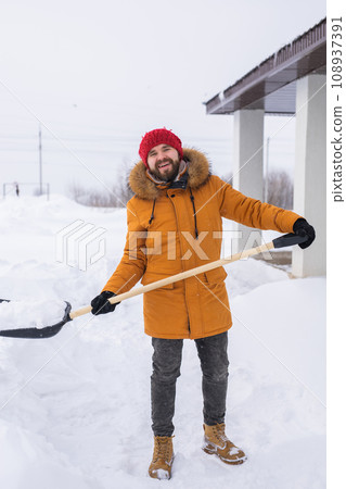 Man removing snow and ice from the sidewalk in front of house. Winter season Man removing snow and ice from the sidewalk in front of house. Winter season 108937391