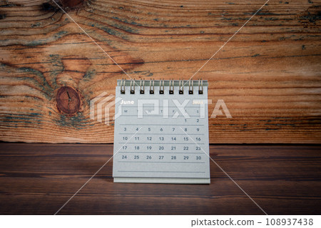 JUNE 2024 cardboard desk calendar on a wooden texture background 108937438