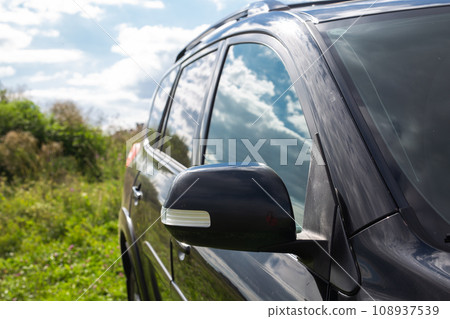 Side rear view mirror on a modern black car outdoor. Close-up of automobile detail Side rear view mirror on a modern black car outdoor. Close-up of automobile detail 108937539